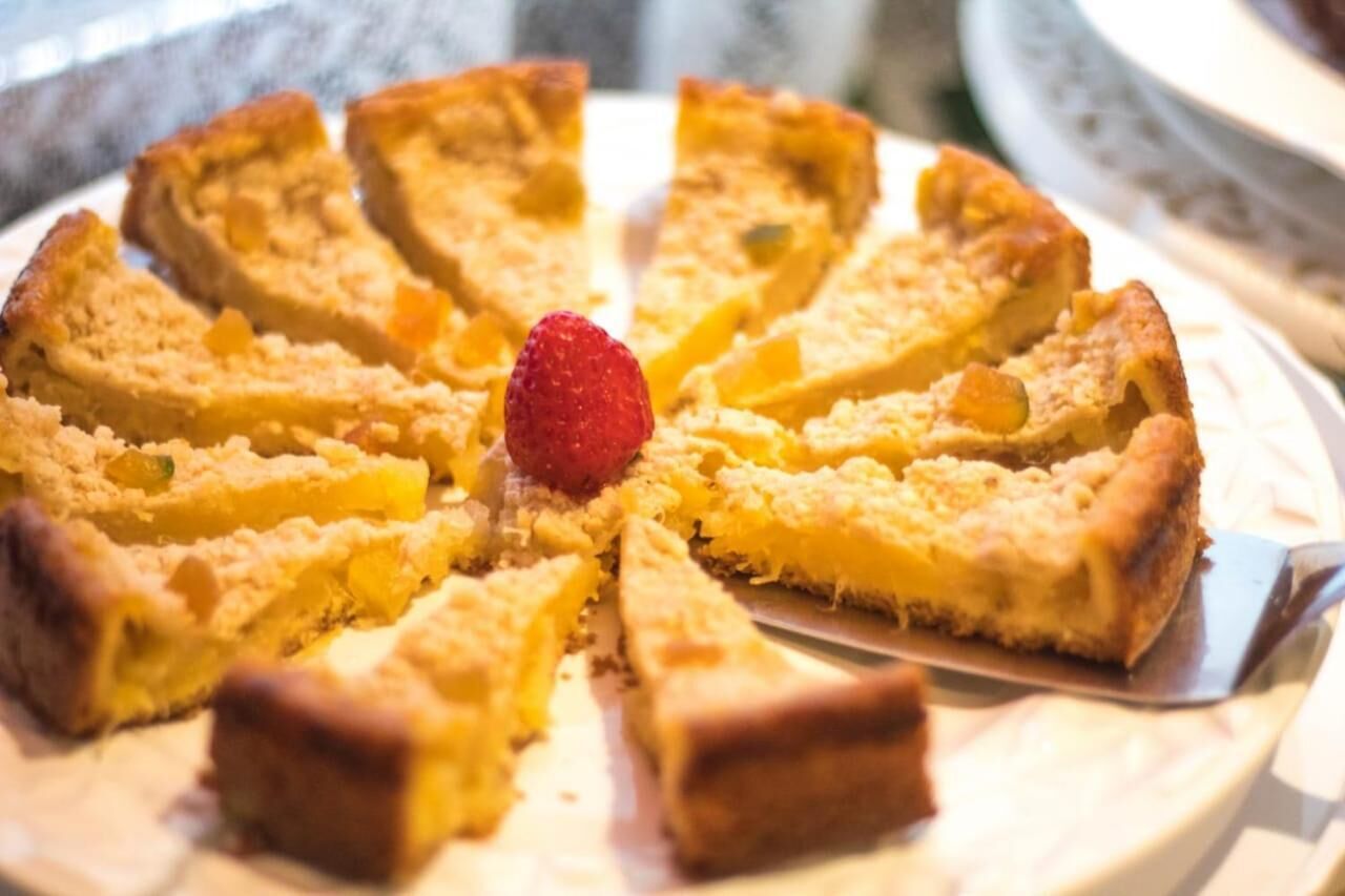 A pie with fruit pieces and a strawberry on top, placed on a plate.