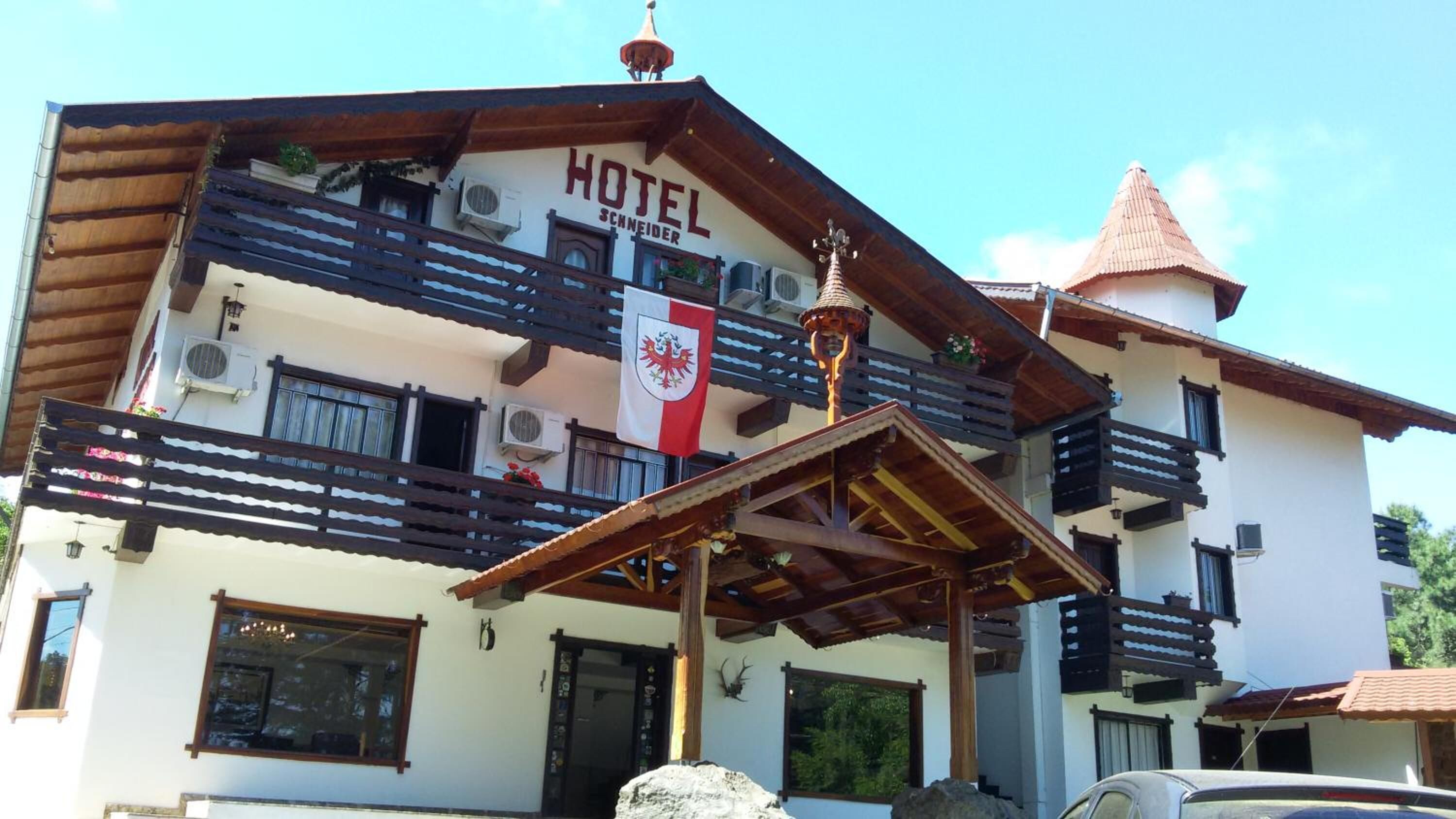 A hotel with a traditional architectural style, featuring balconies, a flag, and a distinctive roof structure.
