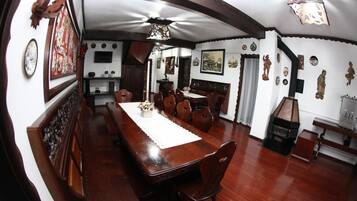 Un comedor con una mesa y sillas de madera, un ventilador de techo y diversos adornos en las paredes.