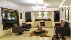 Un salón amplio con chimenea, asientos cómodos y un candelabro.