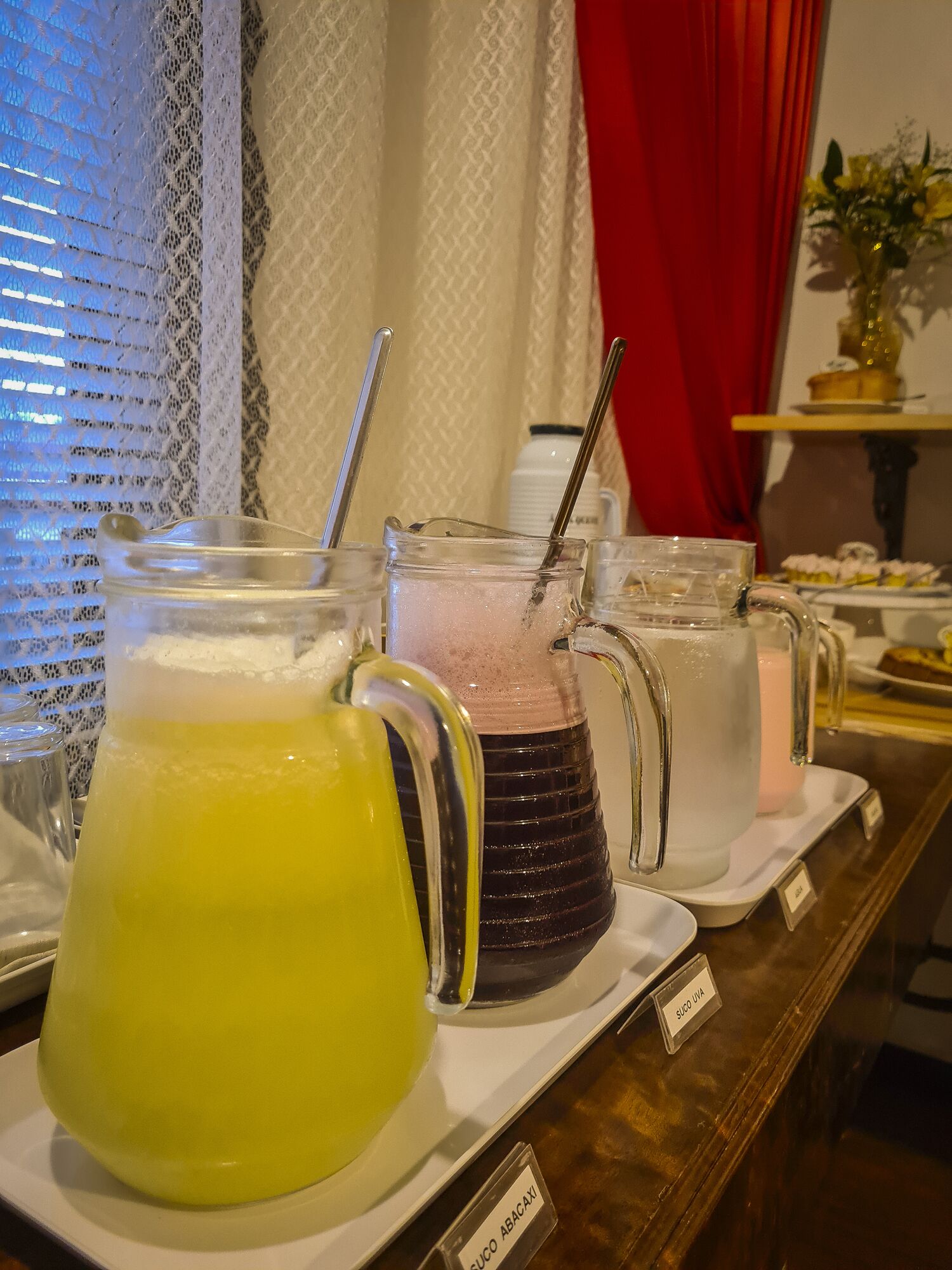 A buffet with various drinks, including a yellow beverage and a pink drink with a straw.