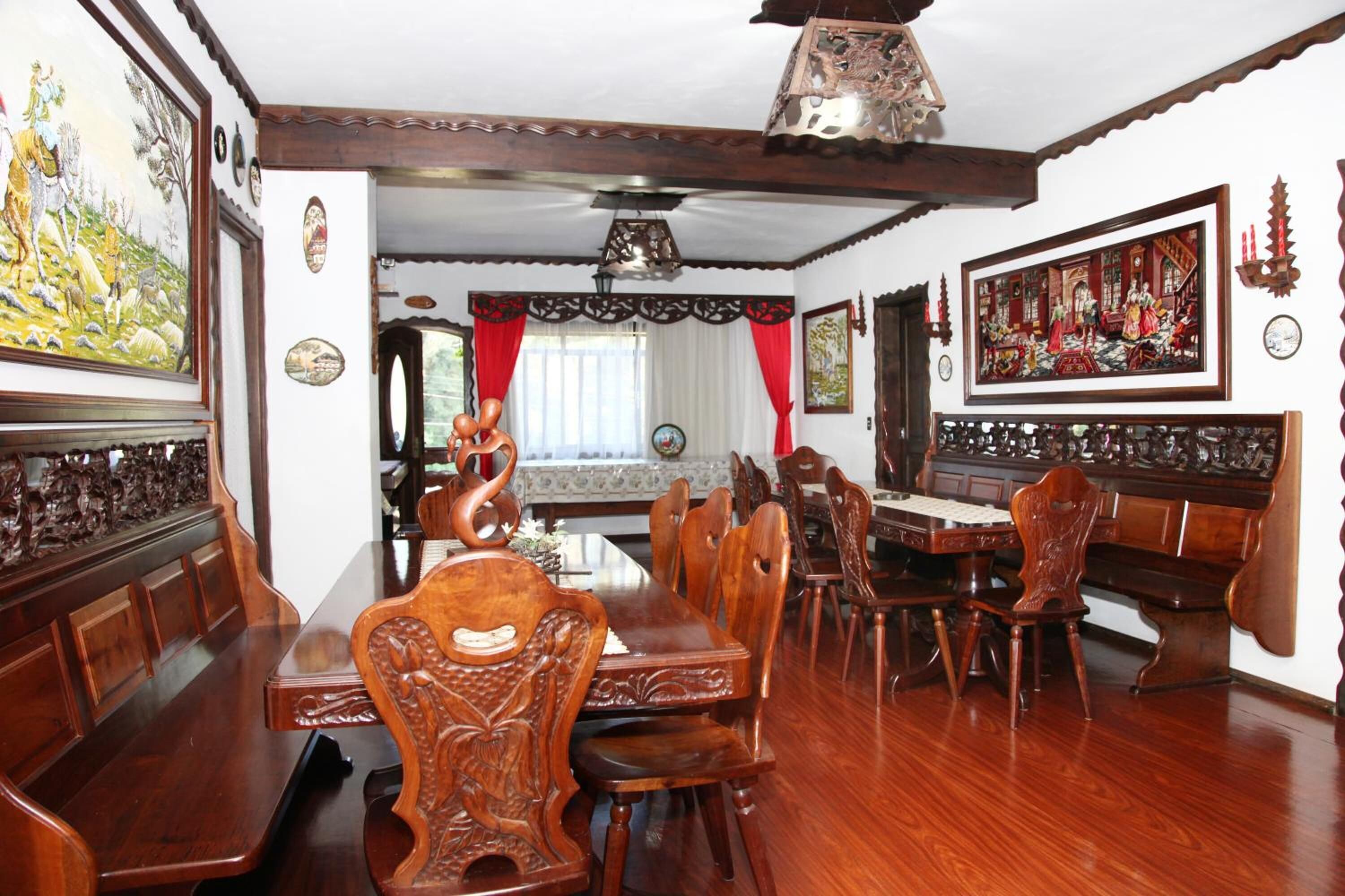 A dining room with wooden furniture, a chandelier, and wall art.