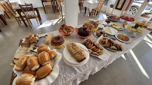 Comedor con mesas dispuestas para un bufé, que ofrece diversas opciones de panadería y repostería.