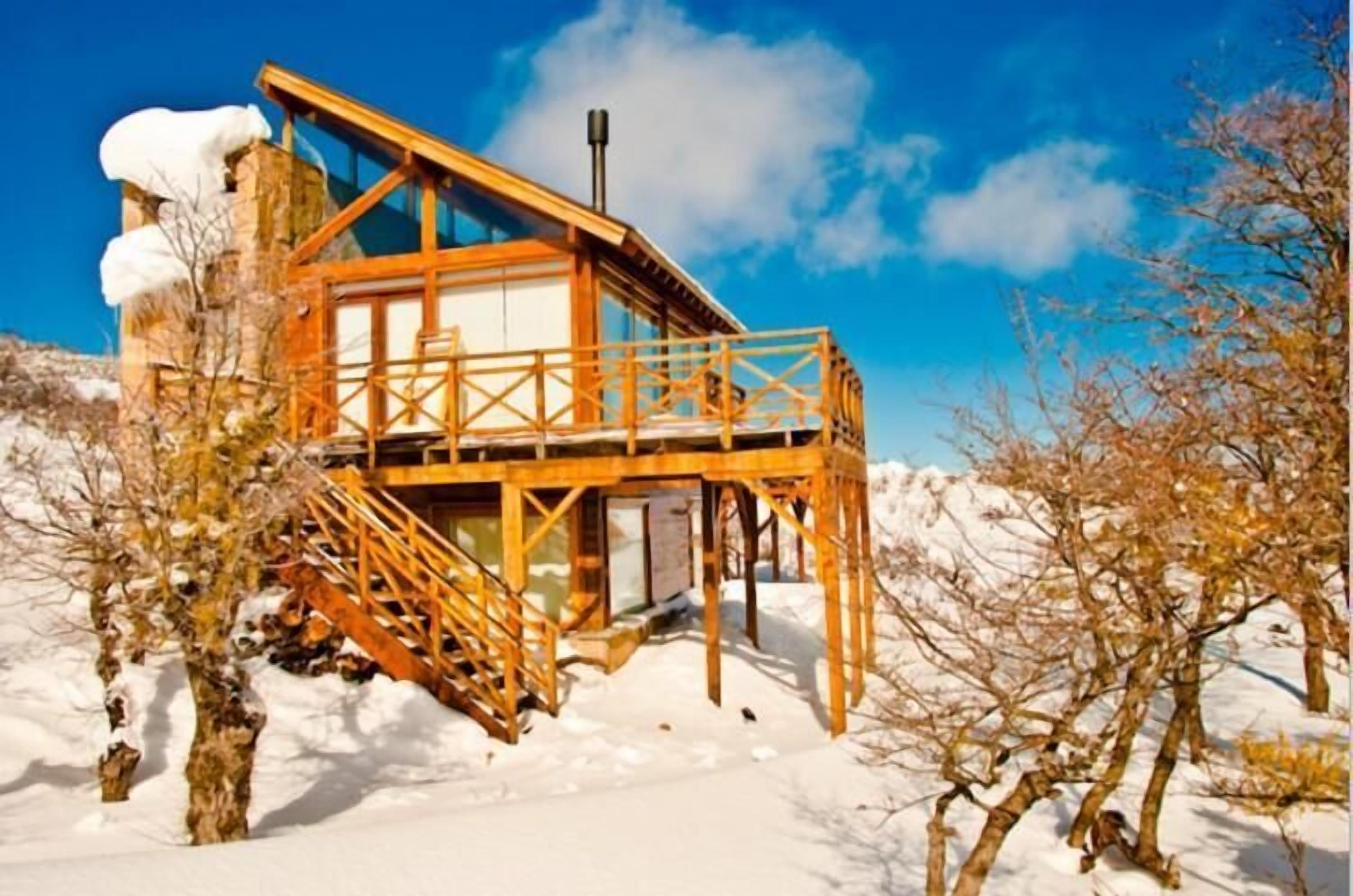 Eine Holzhütte mit Glasfassade, gelegen an einem verschneiten Hang.