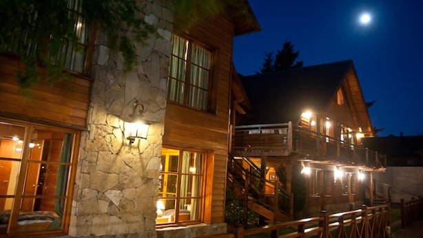 Eine zweistöckige Lodge mit Außenverkleidung aus Stein und Holz, großen Fenstern und einer Treppe, die zum oberen Stockwerk führt.