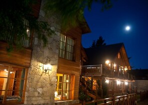 A two-story lodge with stone and wood exterior, large windows, and a staircase leading to the upper level.