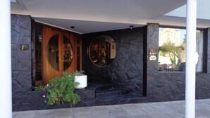 Entrada de un edificio con fachada de piedra, puerta de madera y una planta en maceta.