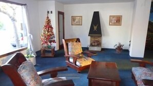 Una habitación con un árbol de Navidad, una chimenea y dos cuadros colgados en la pared.