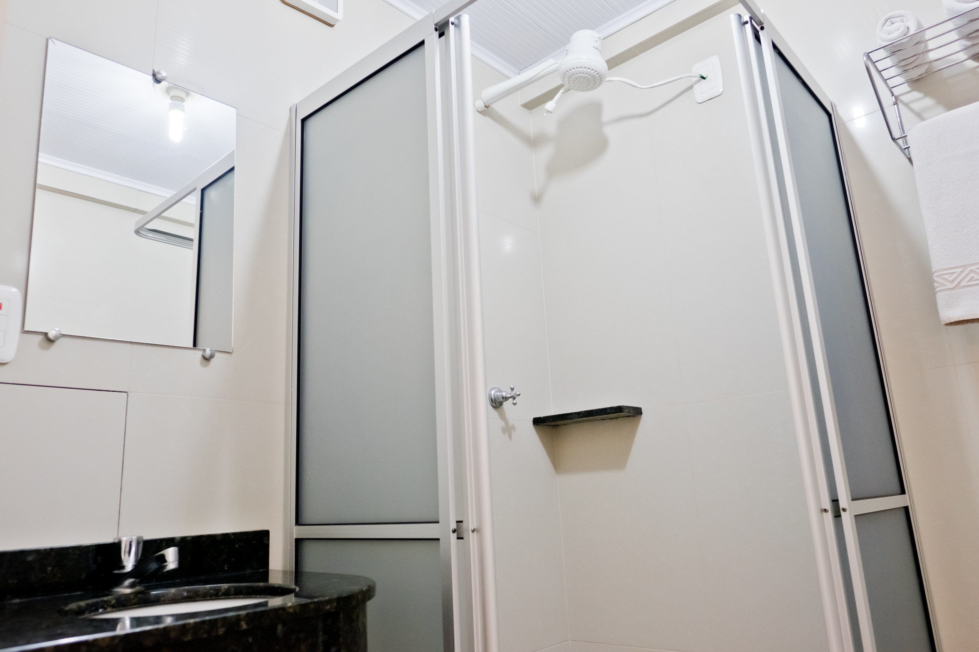 Un baño moderno con cabina de ducha de vidrio, un lavamanos con encimera oscura y un espejo en la pared.