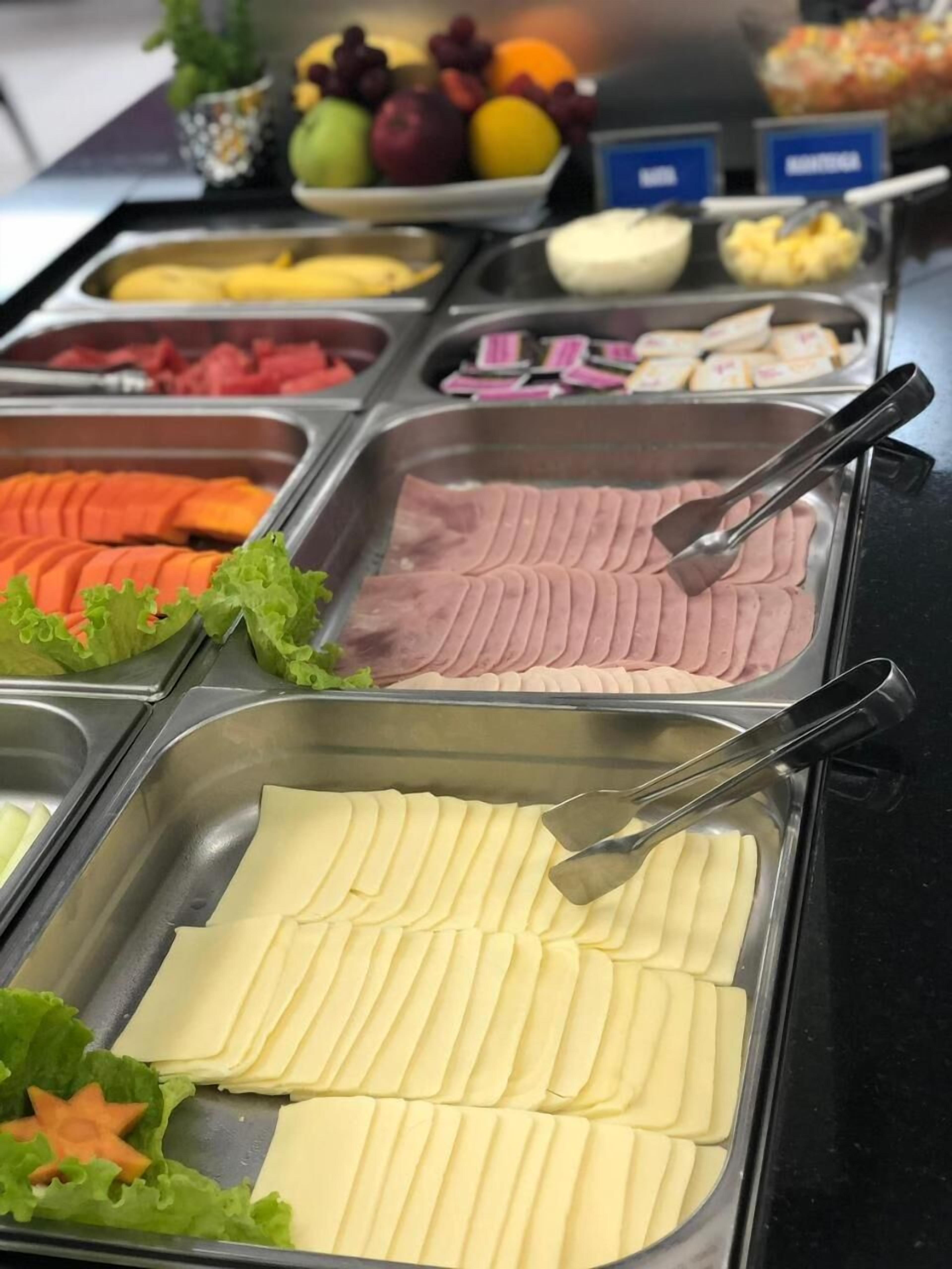 En buffet med forskellige madmuligheder, herunder udskåret kød, oste og frugt.