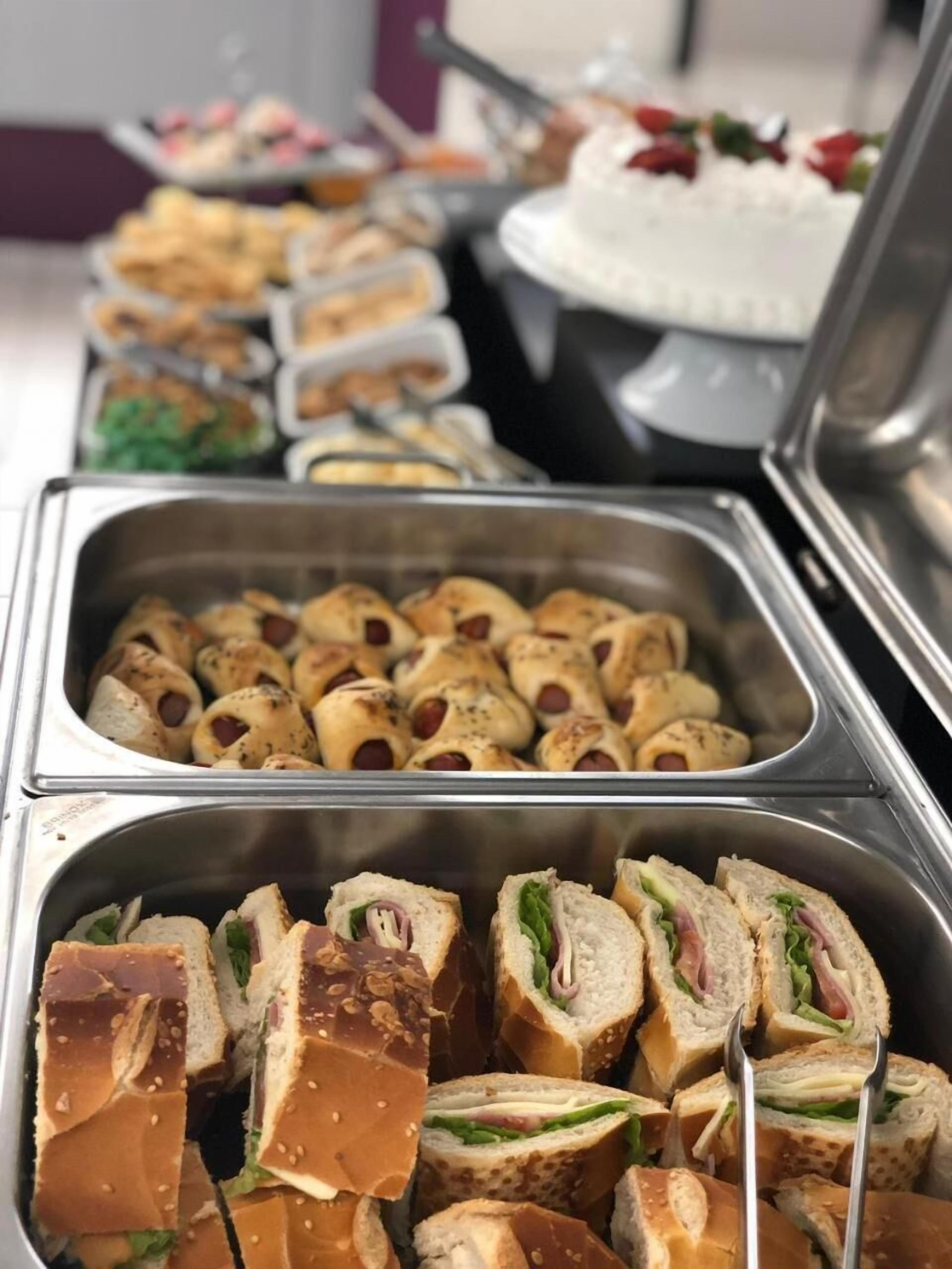A buffet with various food items including sandwiches and rolls.