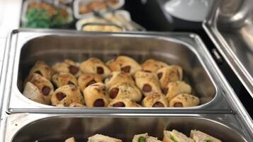 A buffet with various food items including sandwiches and rolls.