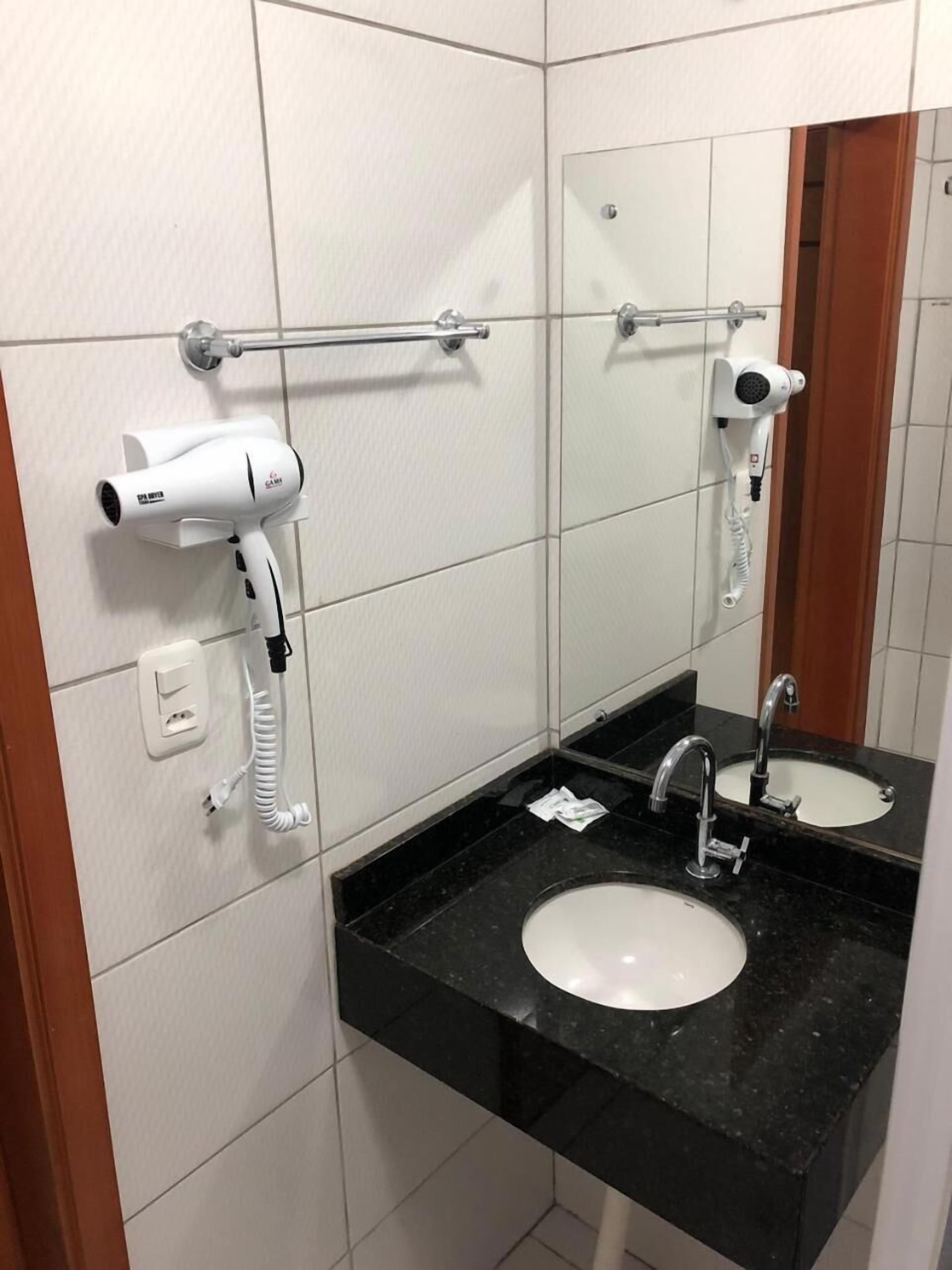 A bathroom with two sinks, a hairdryer, and a towel rack.