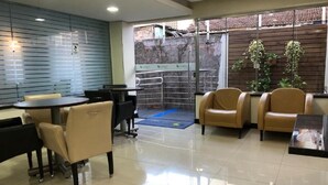 Un moderno vestíbulo de hotel con una mesa redonda y sillas, una partición de vidrio y vistas al exterior.