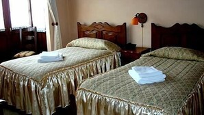 Two single beds with wooden headboards, a bedside table with a lamp, and a chair. - Hostal Santa Teresa de Jesús (Sucre)