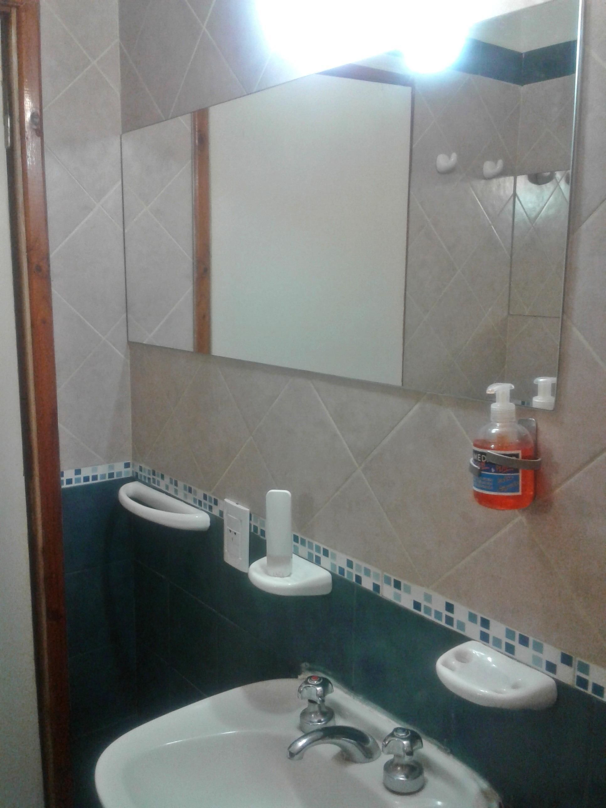 A bathroom with a sink, mirror, and toiletries.