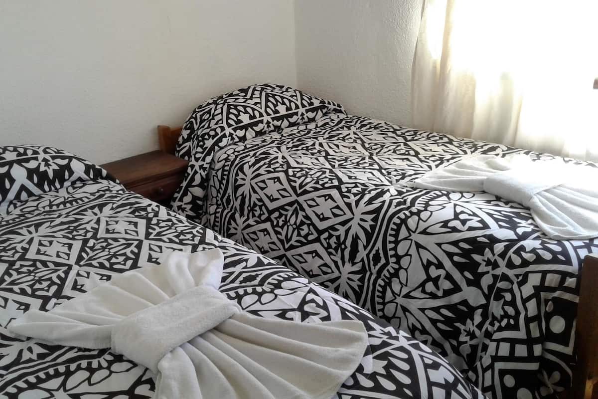 Una habitación con dos camas, cada una con ropa de cama estampada y una toalla blanca en una de ellas.