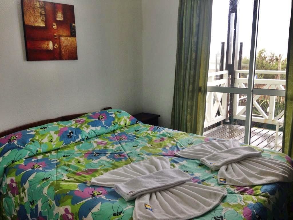 Una habitación de hotel con una cama, un cuadro en la pared y un balcón con barandilla.