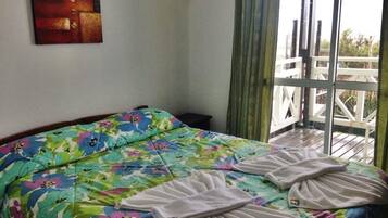 Una habitación de hotel con una cama, un cuadro en la pared y un balcón con barandilla.