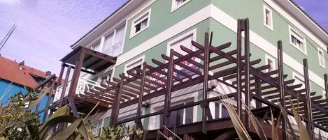 A two-story building with a green and white facade, a wooden balcony structure, and a red-tiled roof.