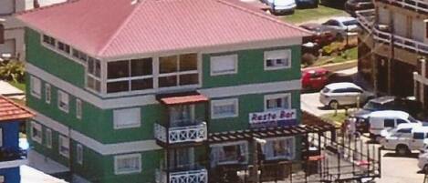 A two-story building with a green facade and a red roof, featuring a 'Resto Bar' sign.