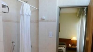 Baño con ducha, bañera y retrete. Hay un perchero y un pasamanos para la ducha.