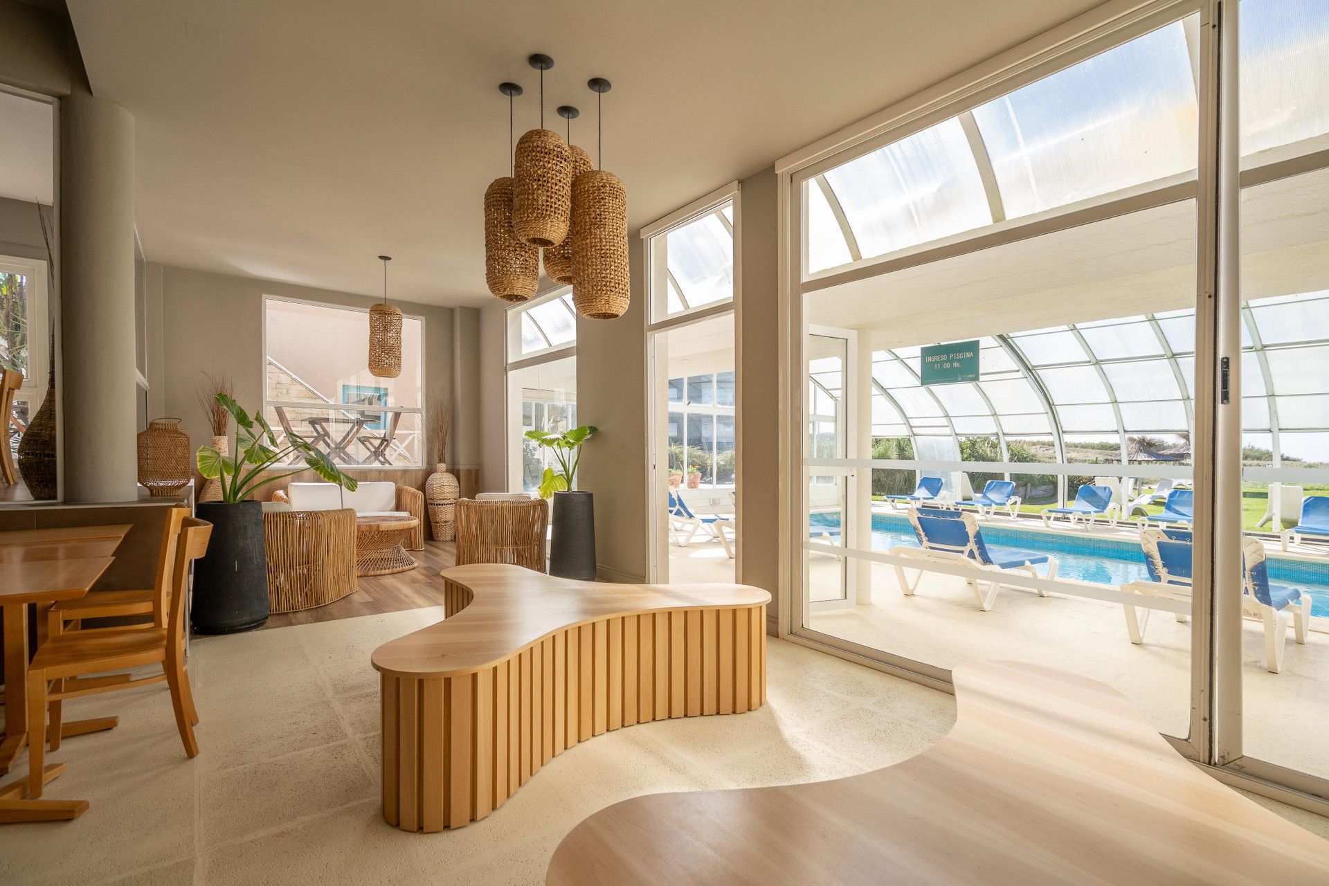 Un interior moderno con un área de piscina visible a través de amplias ventanas.