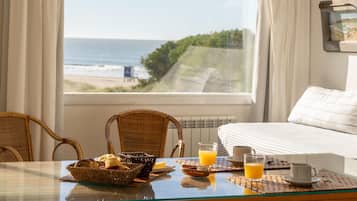 Una mesa de desayuno con vista a la playa y al océano a través de una ventana.
