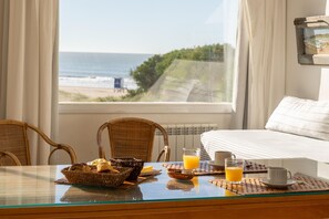 Una mesa de desayuno con vista a la playa y al océano a través de una ventana.