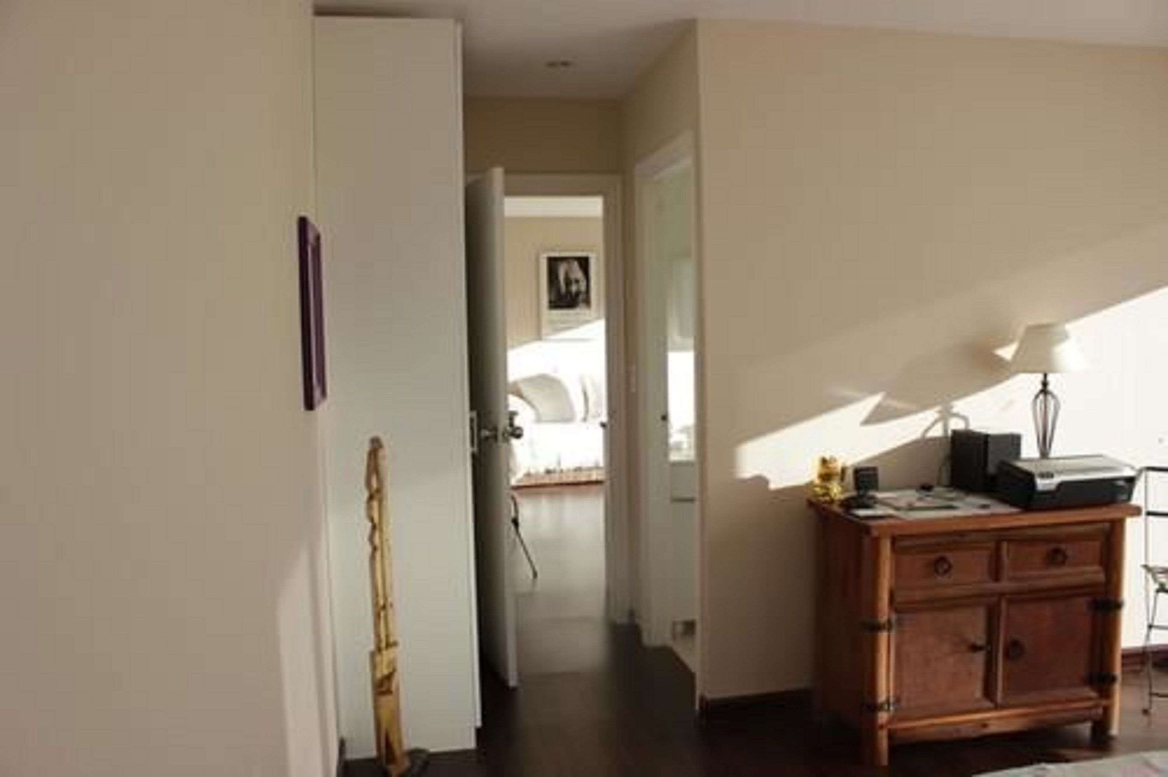 Une chambre d’hôtel avec un bureau en bois, une lampe et un lit en arrière-plan.