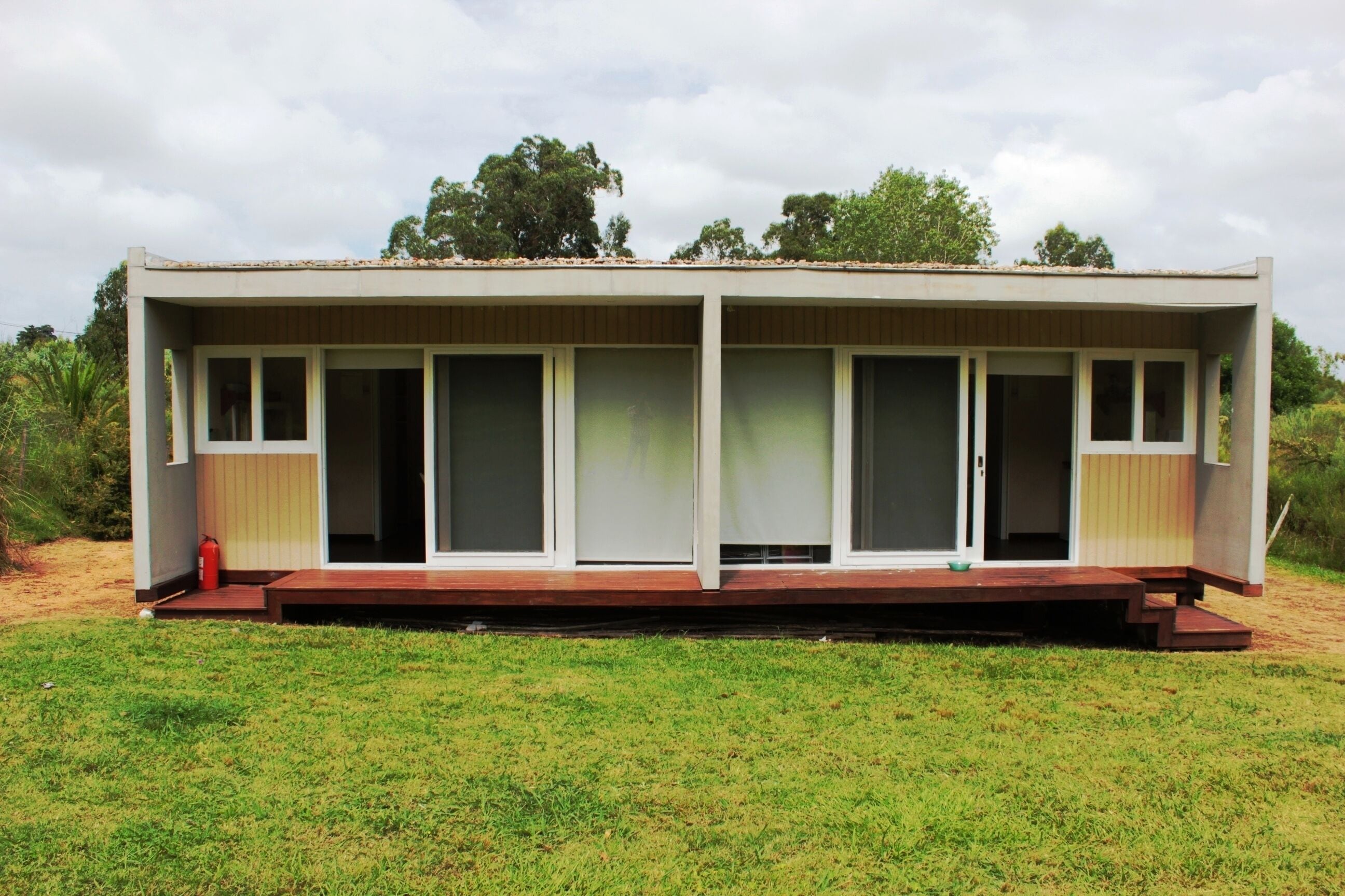 A single-story building with a flat roof, large windows, and a wooden deck.