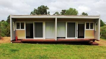 A single-story building with a flat roof, large windows, and a wooden deck.