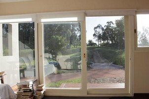 Una habitación con un amplio ventanal corredizo que da a un camino de entrada y vistas a árboles y un coche.