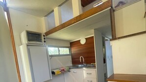 Uma cozinha compacta com micro-ondas, pia e armários de madeira.