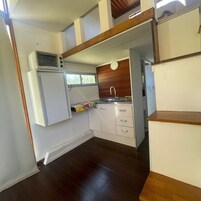 Una cocina compacta con microondas, lavamanos y armarios de madera.