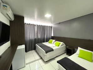 A hotel room with a bed, a desk, a TV, and a window with curtains. - Rezende Suites Hotel (Balneário Camboriú)