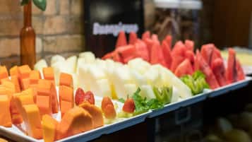Eine Obstauslage mit verschiedenen Früchten, darunter Mangos, Erdbeeren und Wassermelone.