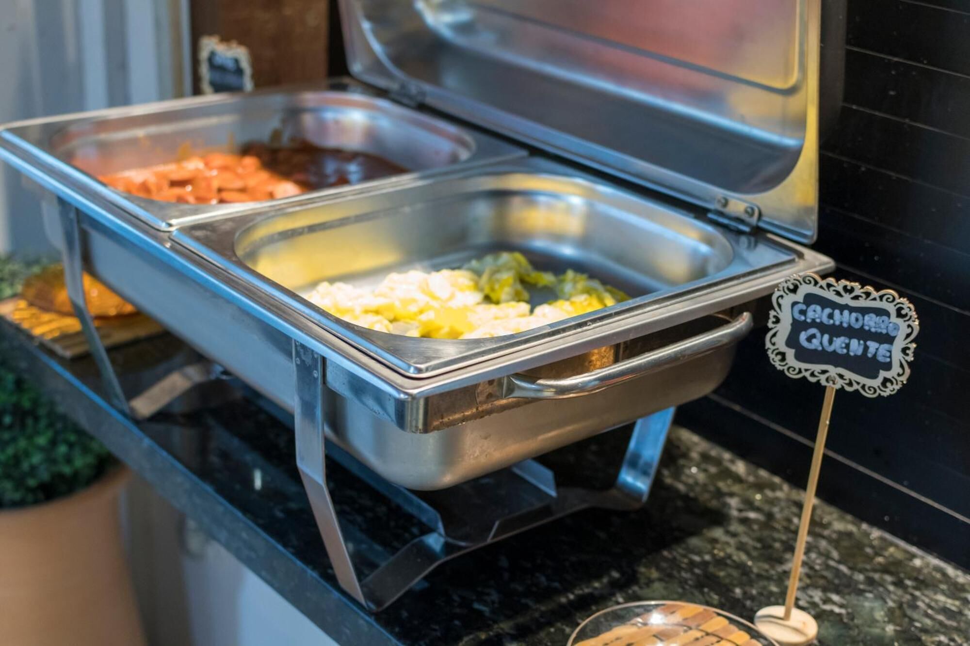 Un bufé con diversos alimentos, incluyendo un cartel que dice 'Cachorro Quemado'.