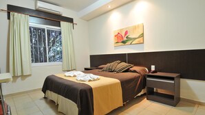 A neatly arranged bedroom with a bed, bedside table, and a window with curtains. - Hotel Casa Nostra (Villa Carlos Paz)