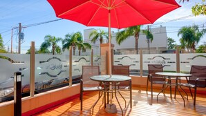 An outdoor patio with a red umbrella, two tables, and four chairs. - Hotel Casa Nostra (Villa Carlos Paz)