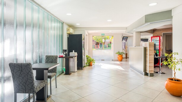 A modern hotel lobby with a reception desk, seating area, and potted plants. - Hotel Casa Nostra (Villa Carlos Paz)