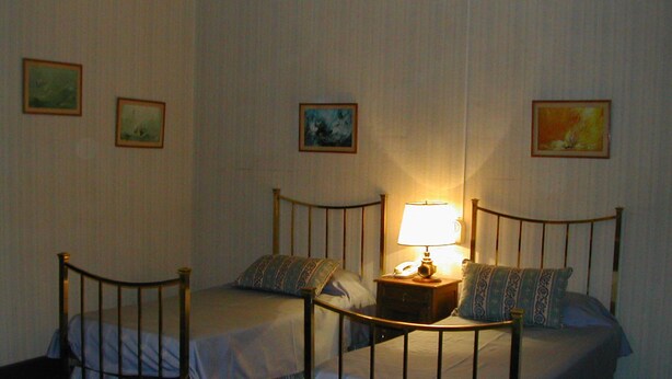 A room with two single beds, a nightstand with a lamp, and three framed pictures on the wall. - Hotel Yacanto (San Javier)