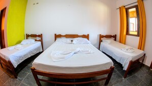 Una habitación con tres camas de madera, cada una con ropa blanca y almohadas.