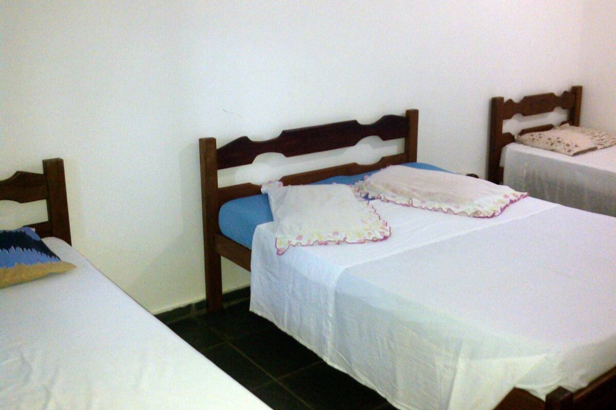 Une chambre avec deux lits simples, chacun doté d’une tête de lit en bois, de draps blancs et d’un oreiller bleu.