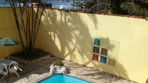 Una piscina con baldosas de piedra, un muro amarillo y una antena parabólica.