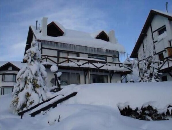 Un edificio cubierto de nieve con estilo arquitectónico tradicional, que destaca por un techo pronunciado y vigas de madera.