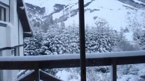 A snow-covered mountain landscape visible through a window. - Departamento Navacerrada (San Carlos de Bariloche)