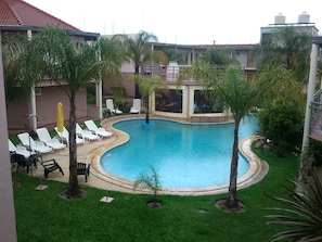 A swimming pool surrounded by palm trees and white lounge chairs.