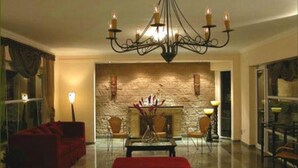 A spacious living room with a large chandelier, a fireplace, and a red sofa. - Hotel Paraíso Termal (Federacion)