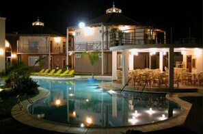 Un hôtel doté d’une piscine, d’un espace extérieur aménagé et d’une terrasse bien éclairée.